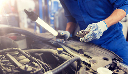 Image showing mechanic man with pliers repairing car at workshop