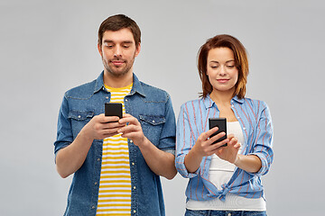 Image showing happy couple using smartphones over grey