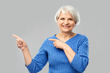 Image showing smiling senior woman pointing fingers to something