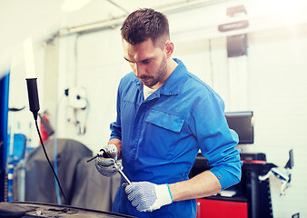 Image showing mechanic man with wrench repairing car at workshop