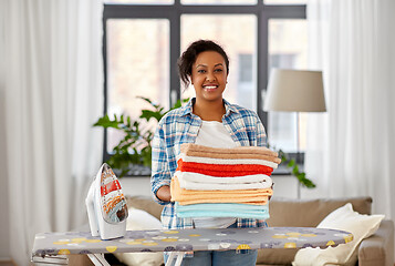 Image showing african american woman with ironed linen at home