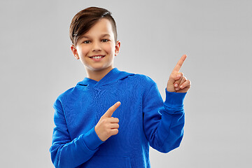 Image showing happy boy in blue hoodie pointing fingers upwards