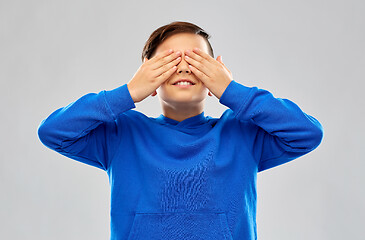 Image showing boy in blue hoodie closing his eyes by hands