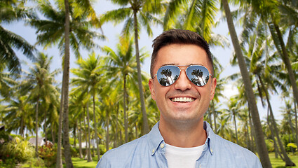 Image showing smiling man in sunglasses over tropical beach