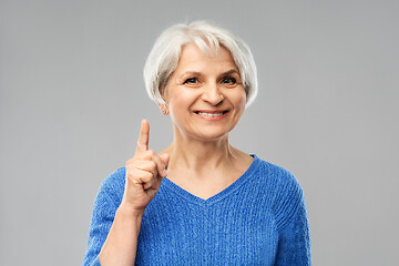 Image showing smiling senior woman pointing finger up