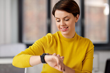 Image showing happy businesswoman using smart watch at office