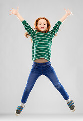 Image showing smiling red haired girl in striped shirt jumping