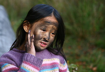 Image showing Portrait of a young cute girl looking at the camera putting coal