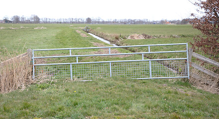 Image showing Metal fence and farm gate leading into grassy field