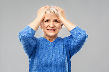 Image showing stressed senior woman holding to her head