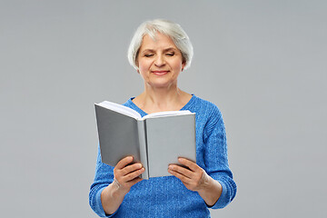 Image showing senior woman reading book over grey background