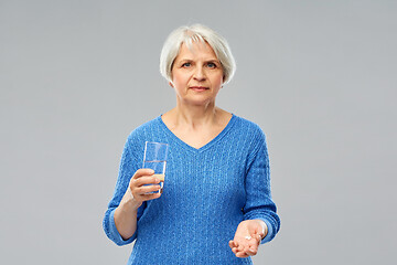 Image showing senior woman with glass of water and pills