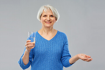 Image showing senior woman with glass of water and pills