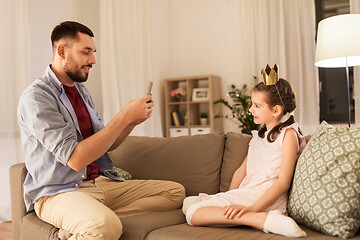 Image showing father photographing daughter by cellphone at home