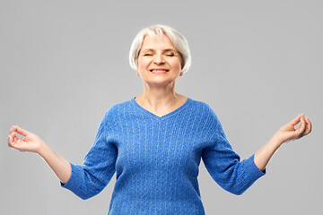 Image showing smiling senior woman in blue sweater chilling