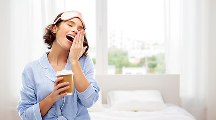 Image showing woman in pajama and eye mask with coffee yawning