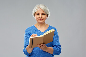 Image showing senior woman writing to diary or notebook