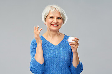 Image showing smiling senior woman with jar of face cream