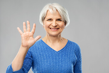 Image showing smiling senior woman showing palm or five fingers