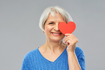 Image showing smiling senior woman covering eye with red heart