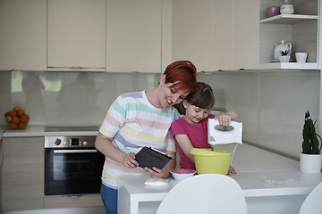 Image showing Mother and daughter playing and preparing dough in the kitchen.