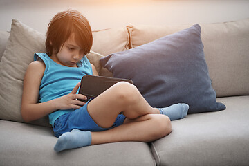 Image showing Little Arabian boy sitting on sofa and playing game on digital t