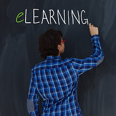 Image showing Teen Boy with chalk  writing on black chalkboard elearning