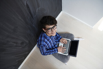 Image showing Arab teenager using laptop to work on homework  at home