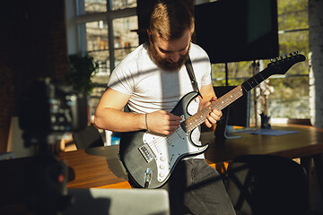 Image showing Caucasian musician playing guitar during online concert at home isolated and quarantined, impressive improvising