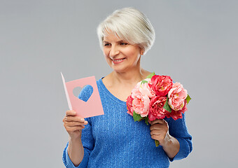 Image showing happy senior woman with flowers and greeting card