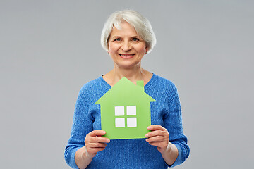 Image showing smiling senior woman holding green house icon