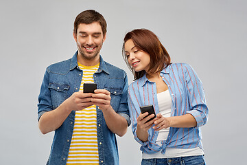 Image showing happy couple using smartphones over grey