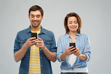 Image showing happy couple using smartphones over grey