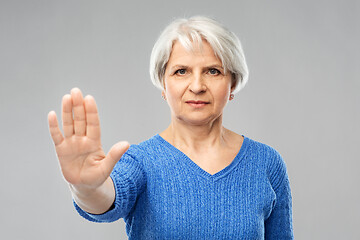 Image showing senior woman in blue sweater making stop gesture