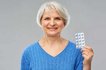 Image showing smiling senior woman with pack of pills