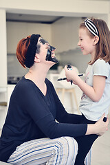 Image showing mother and daughter at home making facial mask beauty treatment