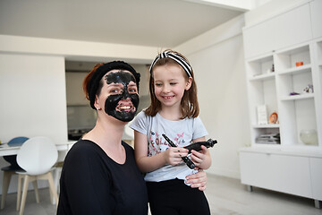 Image showing mother and daughter at home making facial mask beauty treatment