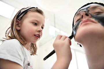 Image showing mother and daughter at home making facial mask beauty treatment