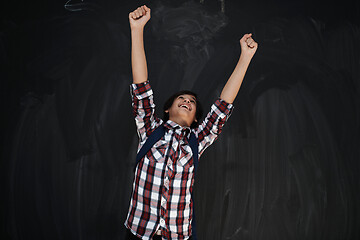 Image showing happy arab teenager  celebrating against black chalkboard