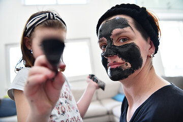 Image showing mother and daughter at home making facial mask beauty treatment