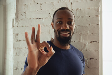 Image showing African-american musician isolared on white brick wall background, cheerful and happy