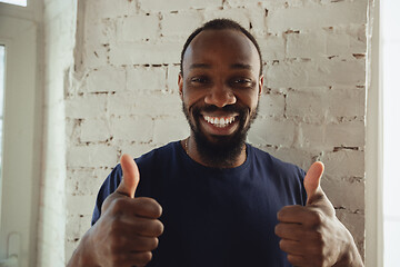 Image showing African-american musician isolared on white brick wall background, cheerful and happy