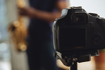 Image showing African-american musician playing saxophone during online concert at home isolated and quarantined, focus on camera