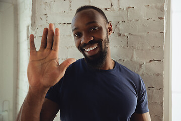 Image showing African-american musician isolared on white brick wall background, cheerful and happy