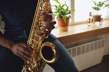 Image showing African-american musician playing saxophone during online concert at home isolated and quarantined, close up