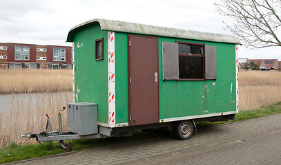 Image showing Old green wooden trailer on wheels stands at the side of the roa