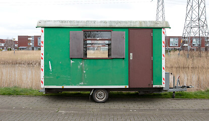 Image showing Old green wooden trailer on wheels stands at the side of the roa