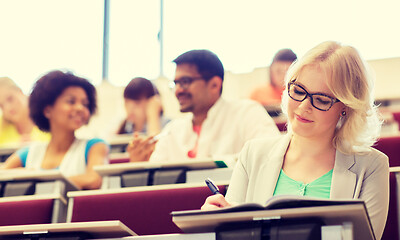 Image showing student girl writing to notebook in lecture hall