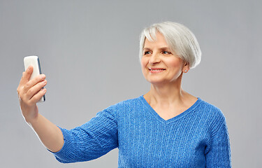 Image showing smiling senior woman taking selfie by smartphone