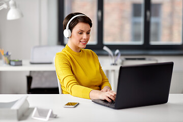 Image showing creative woman in headphones with laptop at office